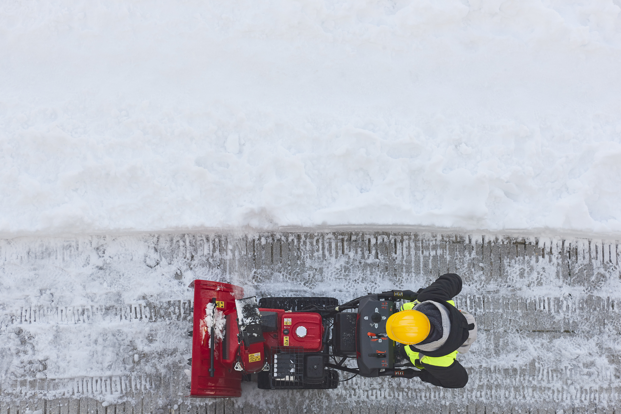 Worker cleaning snow on the sidewalk with a snowblower. Wintertime